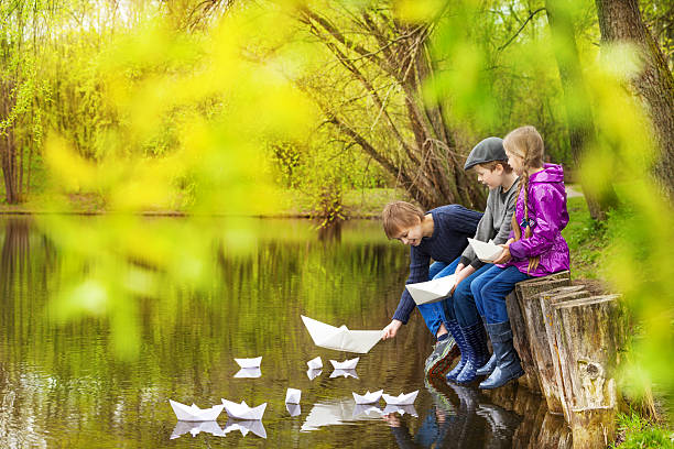 três crianças perto do lago colocar barcos de papel - ticket ticket stub park fun imagens e fotografias de stock