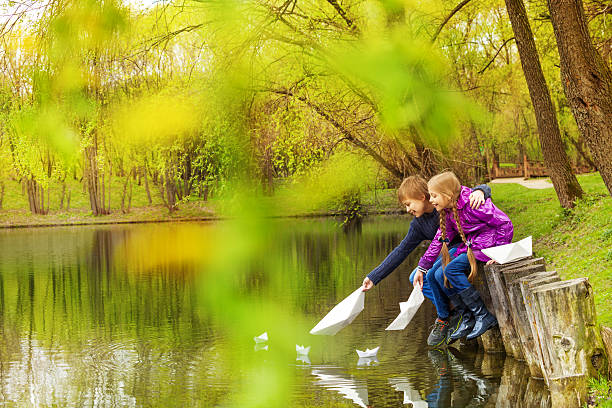 menino e menina perto do lago jogar com barcos de papel - ticket ticket stub park fun imagens e fotografias de stock