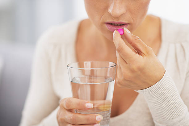 istock closeup on young woman eating pill 480082341