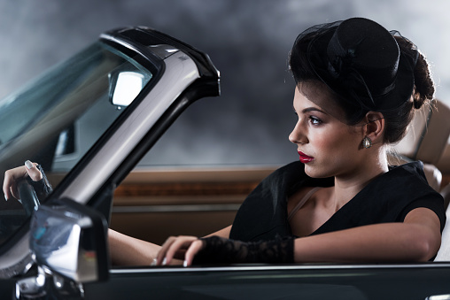 Beautiful retro styled woman driving in a collector's car.