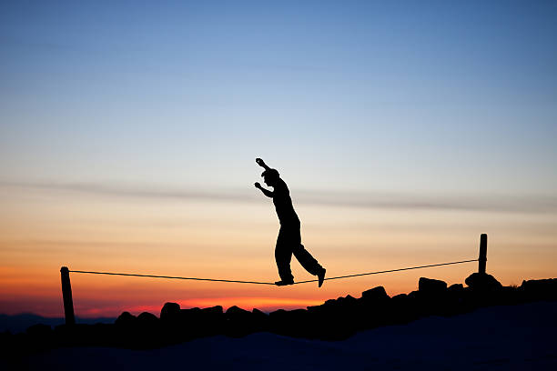 silhouette of slackliner silhouette of slackliner in sunset sky highlining stock pictures, royalty-free photos & images