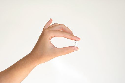 Lady hand holding capsule isolated on white backgroung