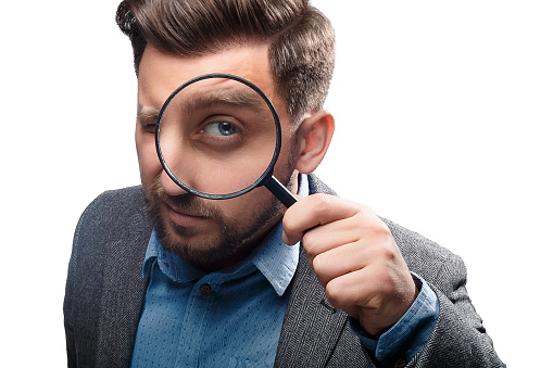 Man in a jacket with magnifying glass isolated on white background