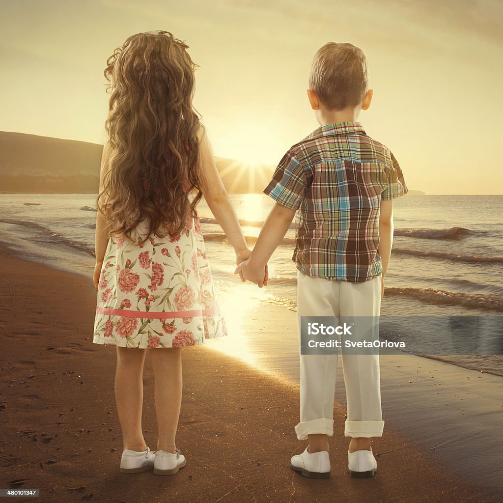 Back view of little kids holding hands at sunset Back view of little girl and boy holding hands at sunset. Love, friendship concept Affectionate Stock Photo