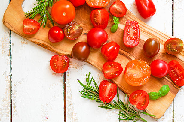 istock Colorful tomatoes on board on wooden background 480105029