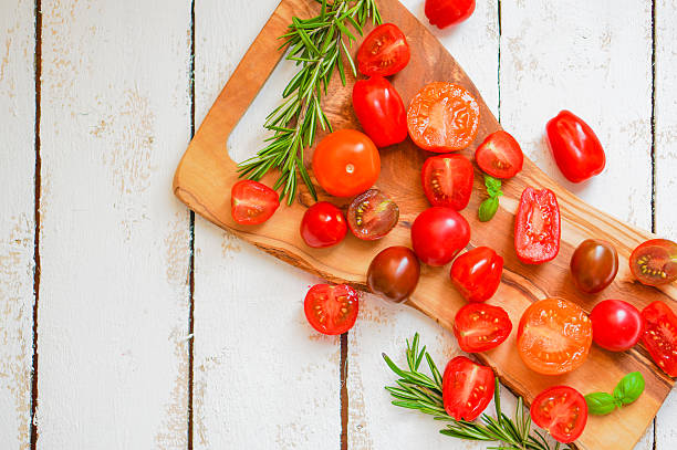 istock Colorful tomatoes on board on wooden background 480105031