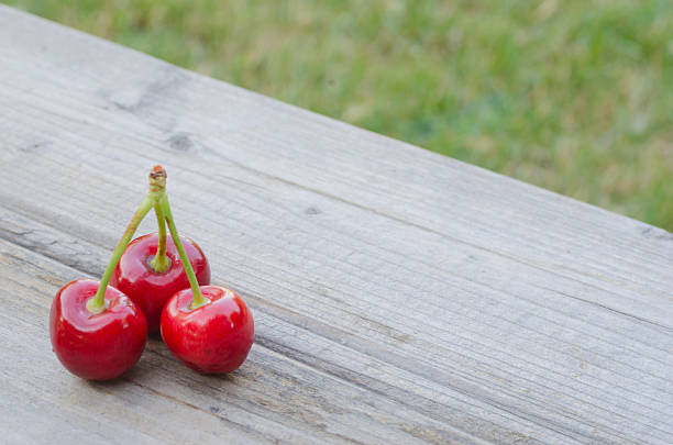 istock 3 cherries isolated on wood 480107188