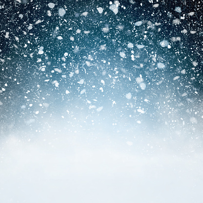 Fluffy snowflakes falling in front of a blue background with vignette - computer generated image