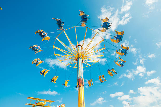 A Ferris wheel with people on it is in the sky. The sky is cloudy and the mood of the image is somewhat somber
