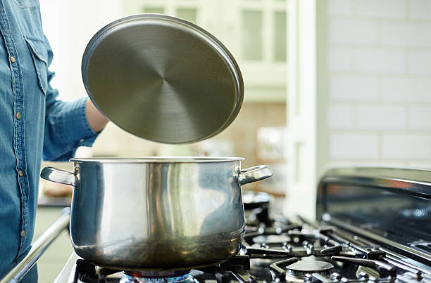 istock Woman lifting steel lid over cooking pan 480113736