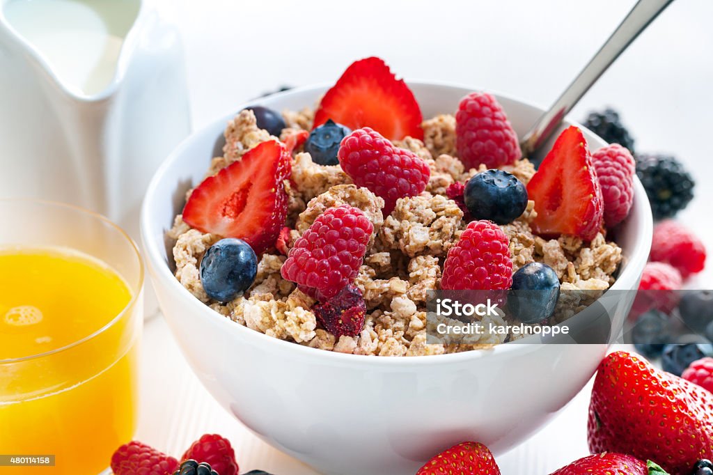 Healthy cereal breakfast with red fruits. Macro close up of Healthy cereal breakfast with red fruits.Bowl of crunchy muesli and fresh orange juice. 2015 Stock Photo