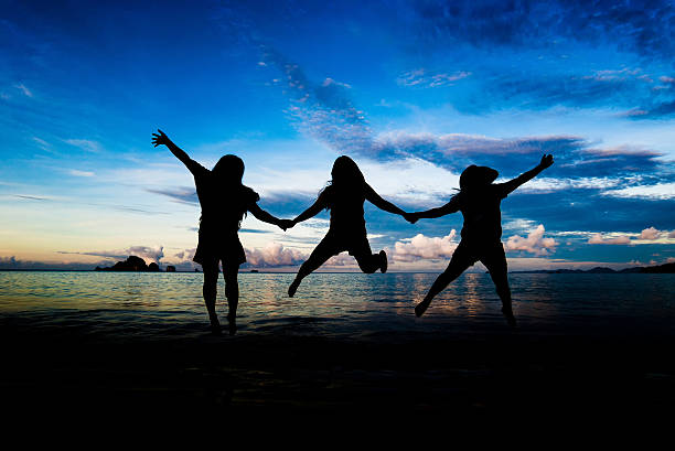 Silhouettes of young group of people jumping stock photo