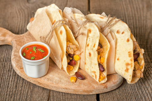 Mexican tortillas with chicken, cheese, corn, red beans and sauce on a wooden surface