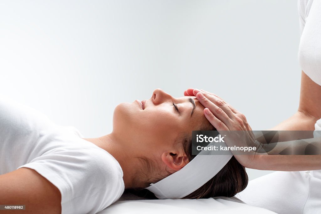 Woman relaxing at reiki session. Close up portrait of young woman relaxing at reiki session.Therapist touching girls head with hands. Reiki Stock Photo