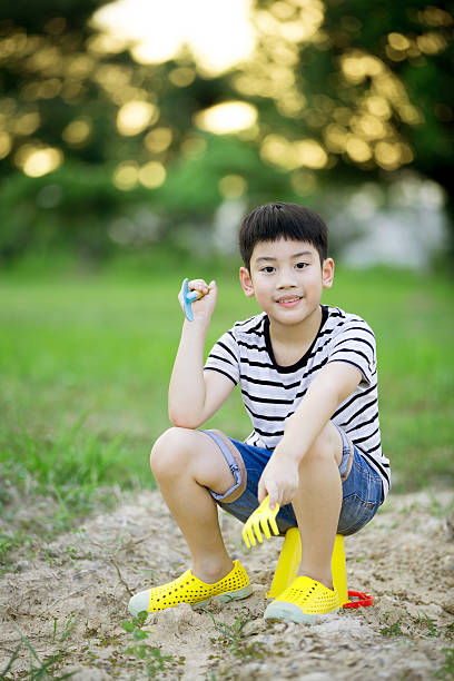 Asian cute boy playing with plastic toys in garden