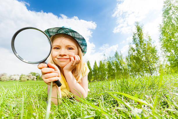 istock Girl holding magnifier lays alone on green grass 480119132