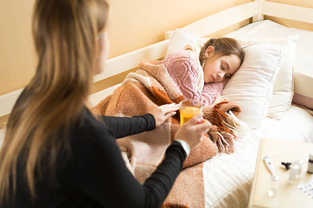 istock caring mother brought hot tea to sleeping sick daughter 480121830