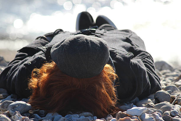 immagine di adolescente ragazzo prendere il sole in inverno a pebble beach - out of season foto e immagini stock
