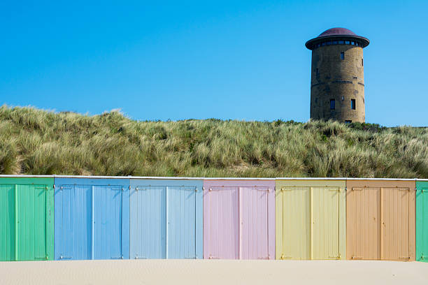 Colored beach houses on the domburg beach marram grass covered dunes and mushroom like water tower