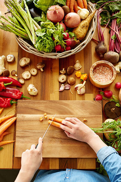 istock Woman cutting carrots on wooden board 480132486