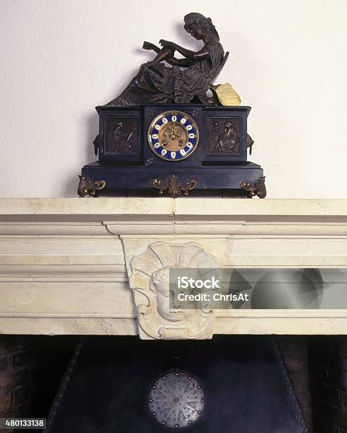 An Antique Clock Stands On An Old Stone Mantelpiece Stock Photo - Download Image Now