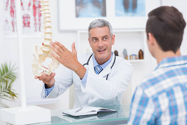 istock Doctor showing his patient a spine model 480136074