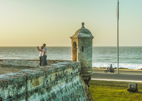 Cartagrna, Colombia - December 31, 2014 : Couple taking a selfie photo colonial spanish fort with caribbean sea at background in Cartagena, the most famous watering place of Colombia.