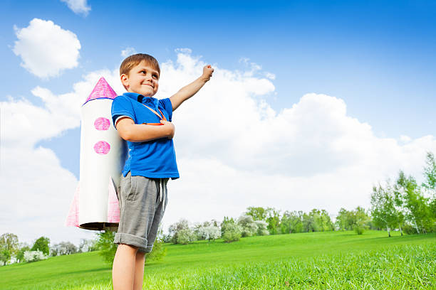 istock Boy wears paper rocket toy and holds arm up 480137650