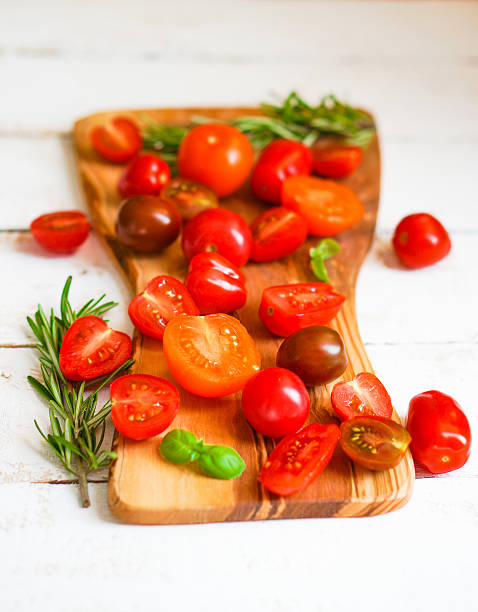 istock Colorful tomatoes on board on wooden background 480139901