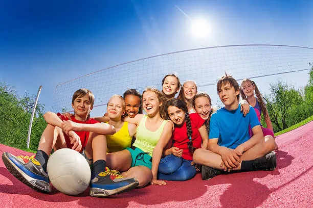 Photo of Happy teenagers who sit on volleyball game court