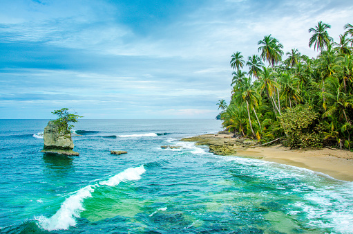 Woman walking along bright and sunny island coastline