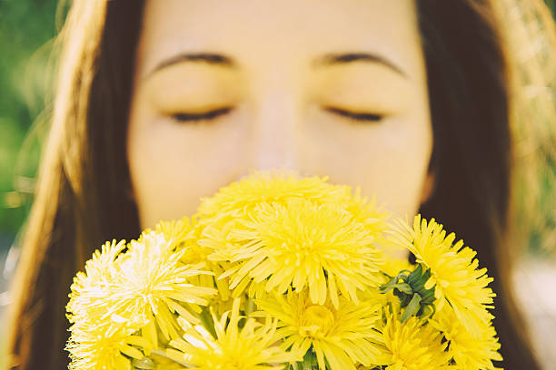 Portrait of beautiful girl with closed eyes with bouquet of yellow dandelions outdoor in summer, concept of summer mood