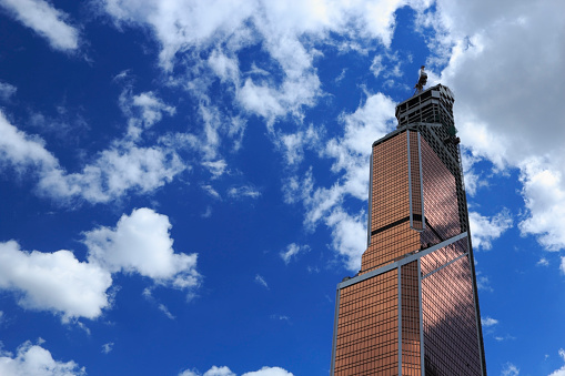 Modern skyscraper under constuction against blue sky.