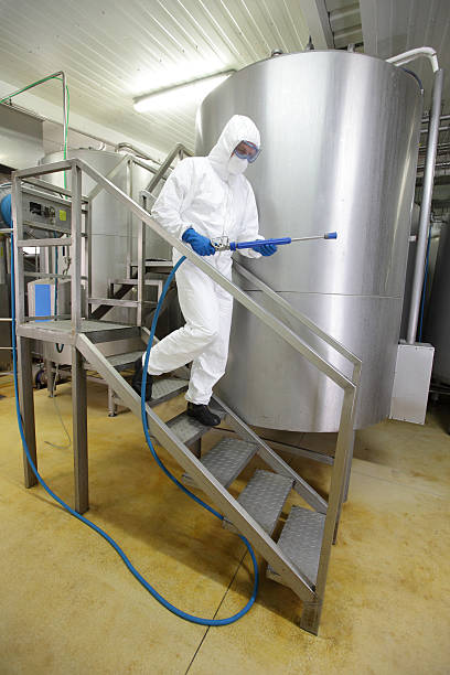 technician with high pressure washer in plant