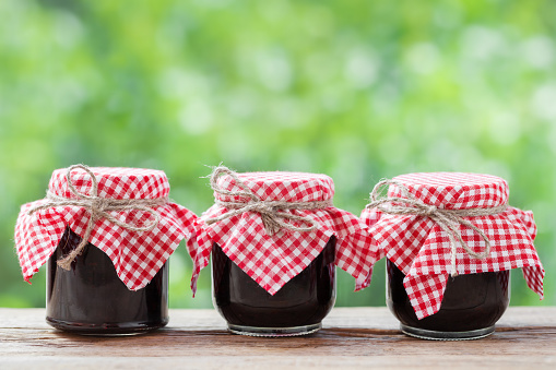 Three jears of jam on rustic table.