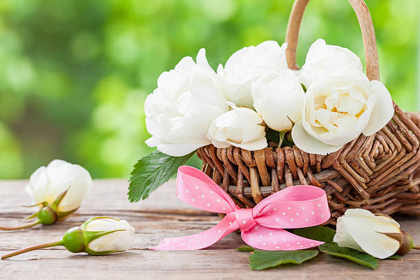 Rustic wicker basket with wild rose flowers and pink ribbon.