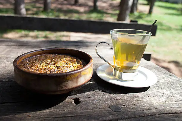 cup of tea in transparent glass and moussaka in ceramic bowl on wooden table