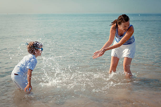 istock Mom and son splashing water at sea 480170271
