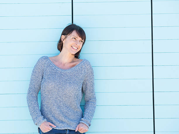 istock Smiling woman standing against blue background 480175820