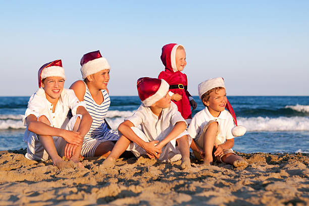 istock Children in santa claus hat are sitting on beach 480176259