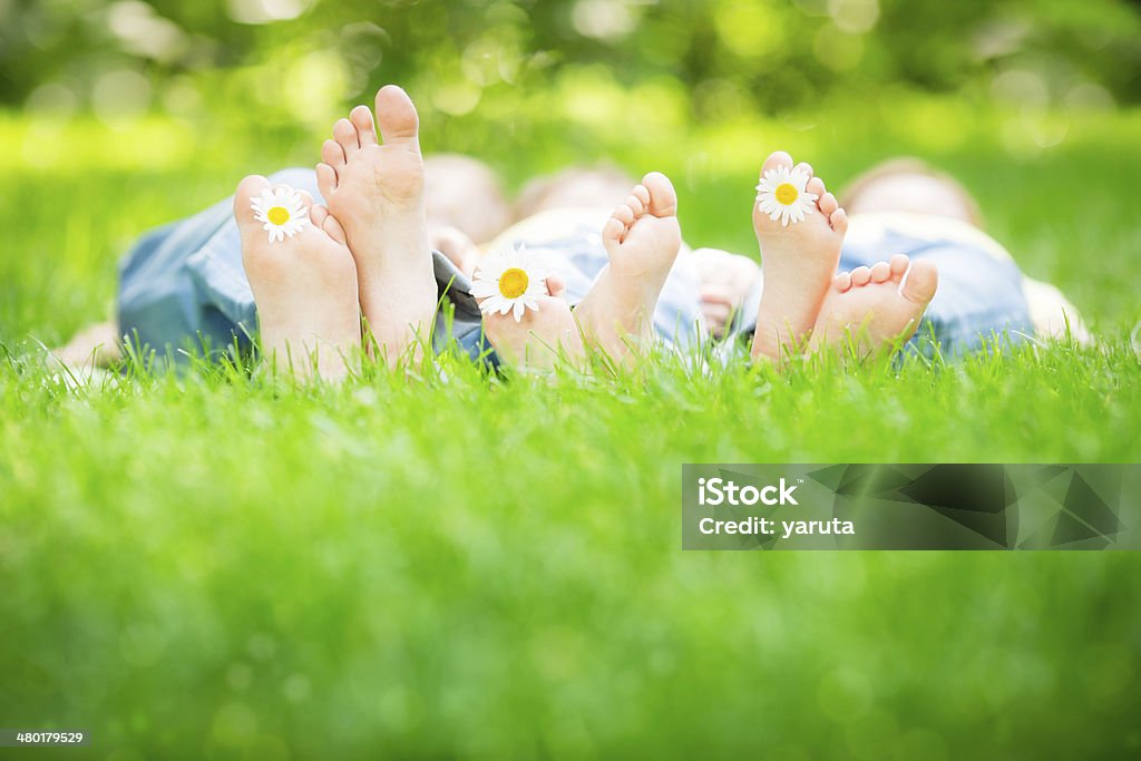 Family lying on grass Family lying on grass outdoors in spring park Barefoot Stock Photo