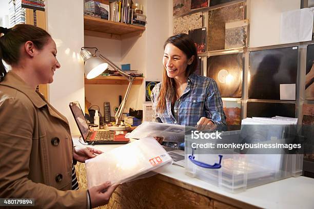 Female Customer Being Served At Counter Of A Record Shop Stock Photo - Download Image Now