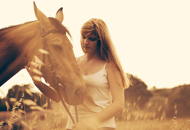 Teen girl ride on white horse without saddle on meadow in late afternoon