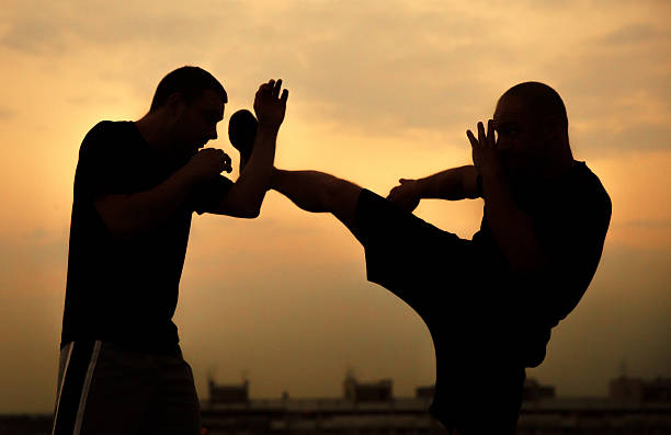 Self defence from leg hit Practicing martial arts on a roof in sunset sidekick stock pictures, royalty-free photos & images