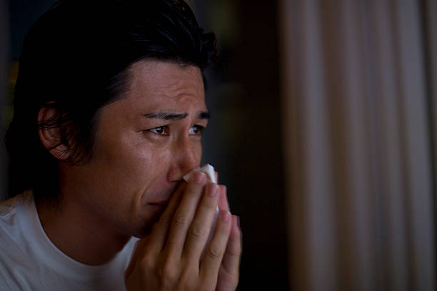 Man blowing his nose with tears Man blowing his nose man crying stock pictures, royalty-free photos & images