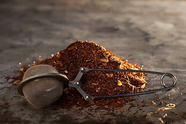 Photo of Rooibos Tea and tea-strainer on a metal texture