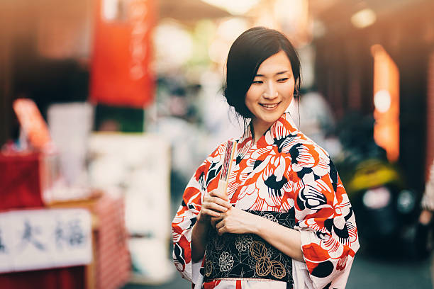 Portrait of beautiful japanese woman The portrait of beautiful japanese woman. She stand outside and wear kimono and obi. The kimono is very colorful and elegant. She smile and seems to be happy. kimono stock pictures, royalty-free photos & images