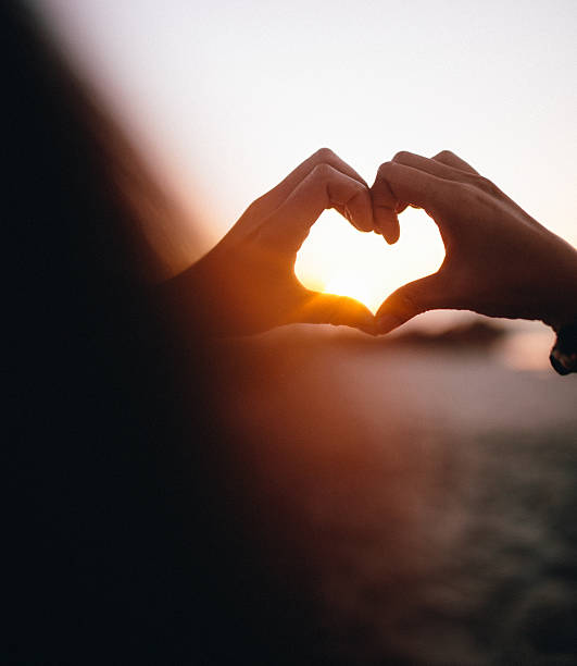 istock Girl making a heart silhouette with her hands at sunset 480187998