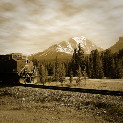 Freight train approach to Lake Louise station in Canadian rockies. Vintage style.