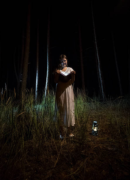 istock woman in nightgown reading book at night forest 480188328
